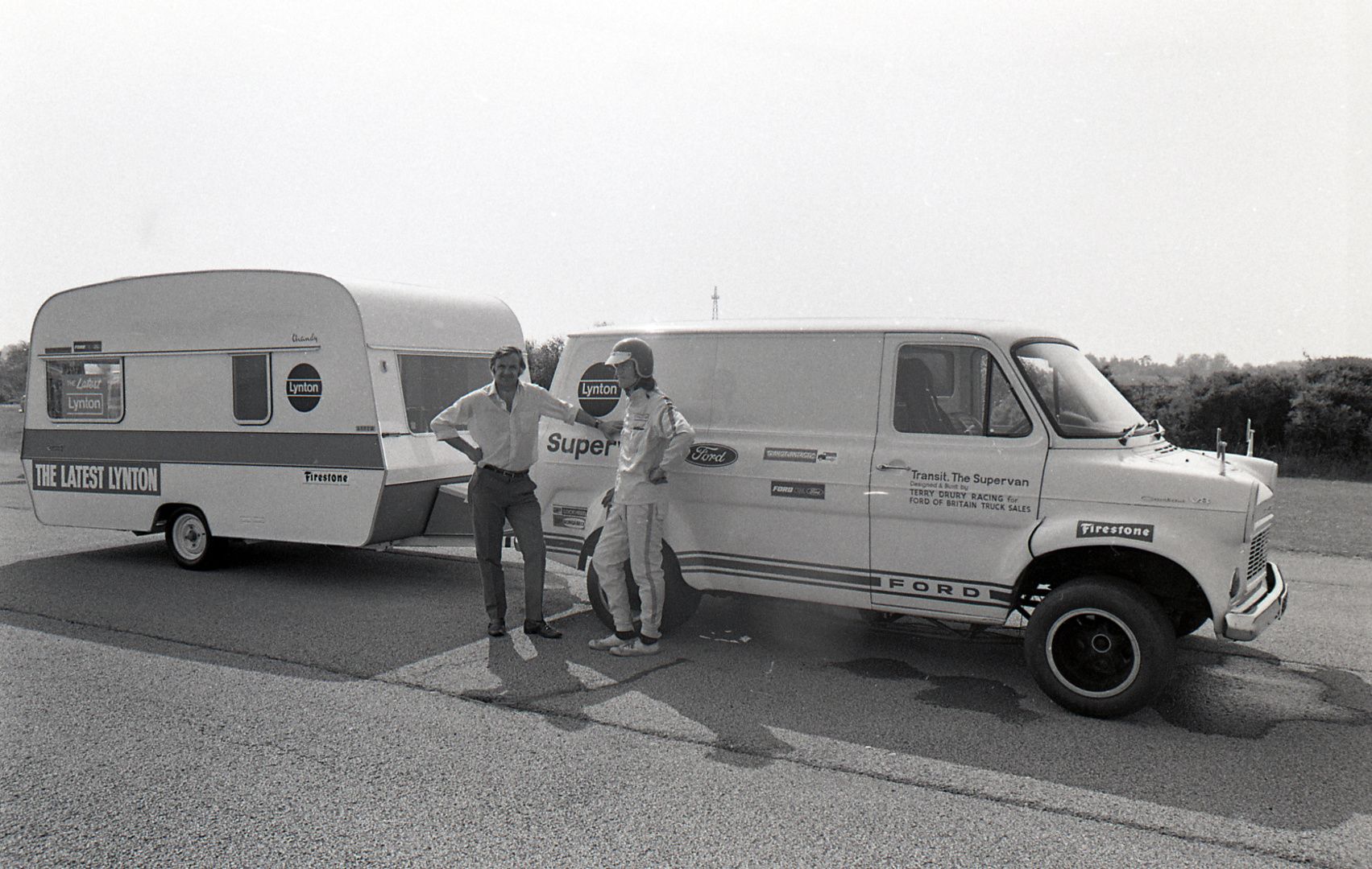 Archive image of Terry Drury talking to a driver in a racing suit, stood by Supervan and a caravan