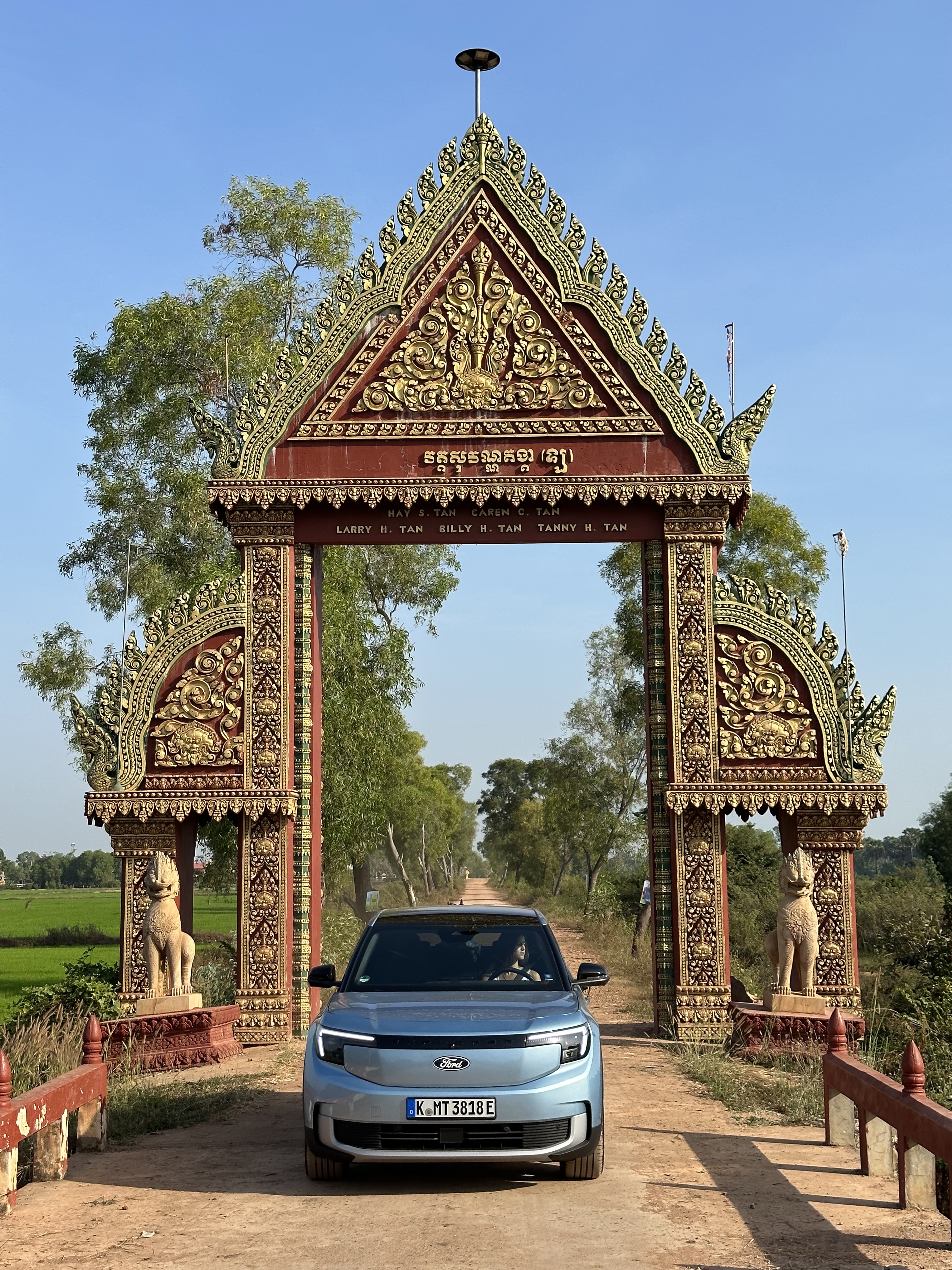 A blue car underneath a thai gate