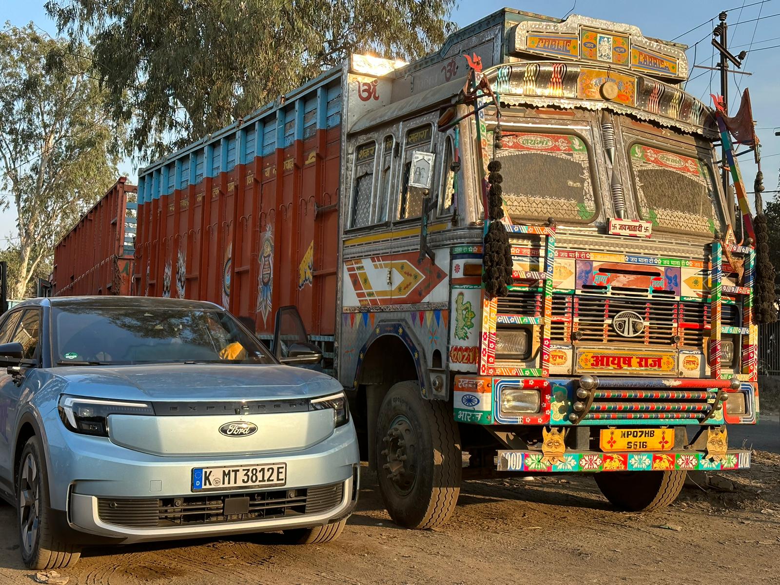 A blue SUV in a next to a colourful truck