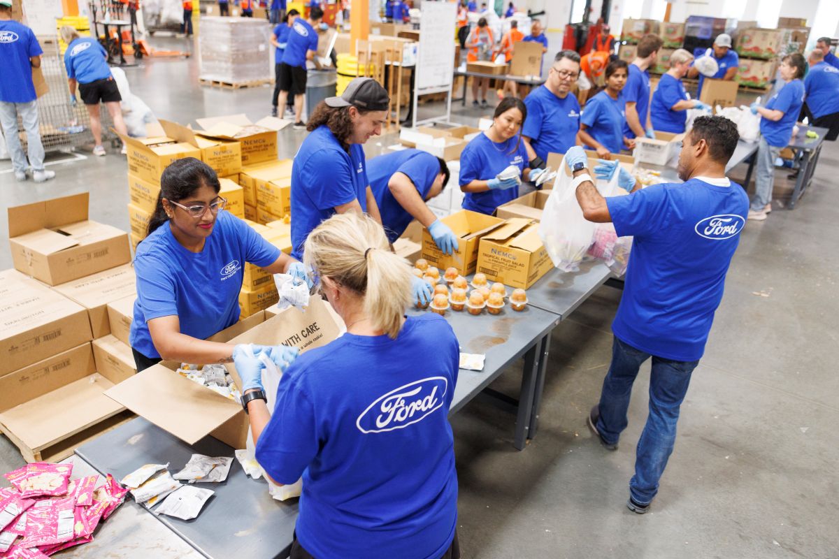 A group of Ford employee volunteers pack food items for donation.