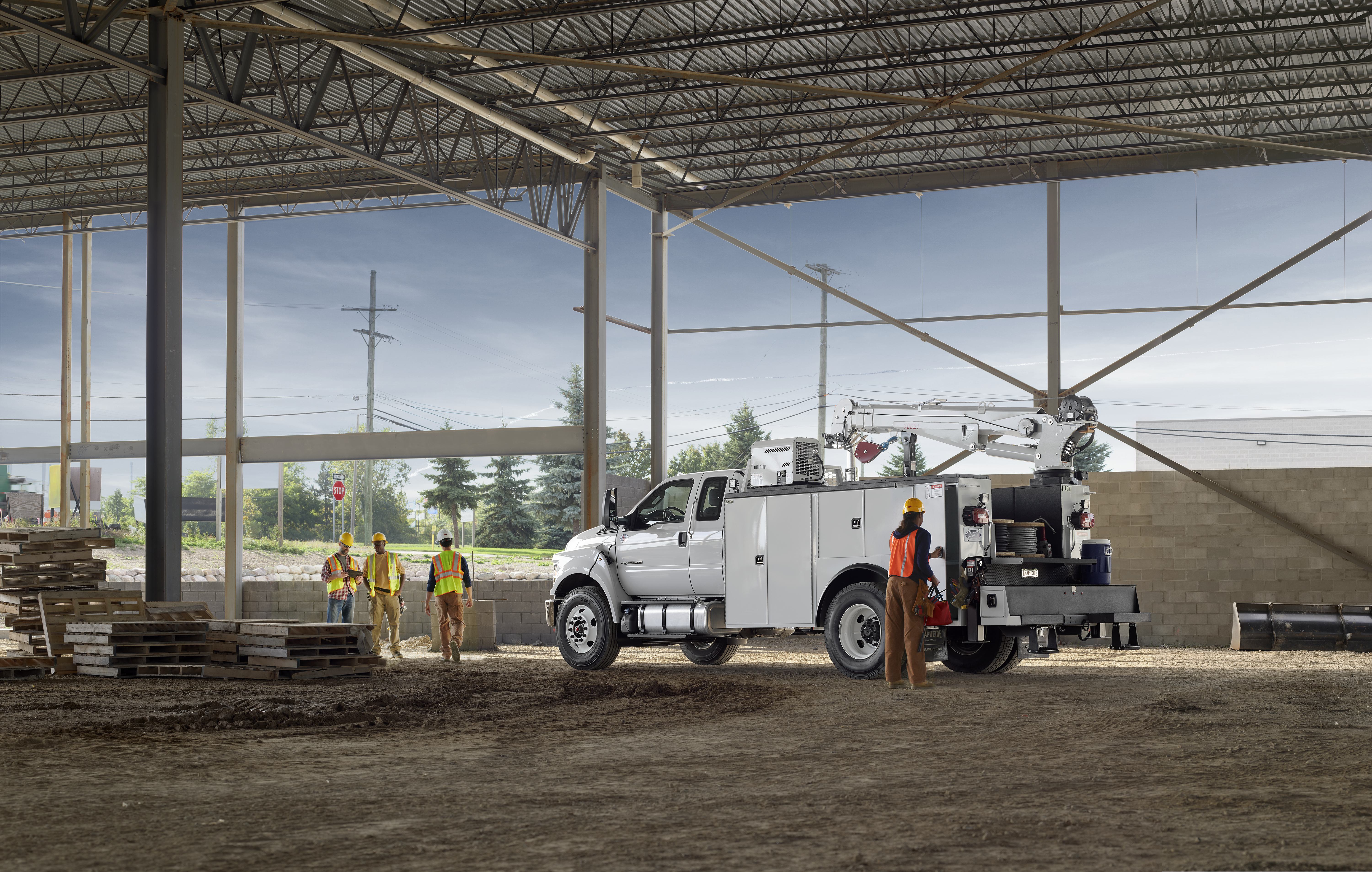 A construction crew works near a large white vehicle