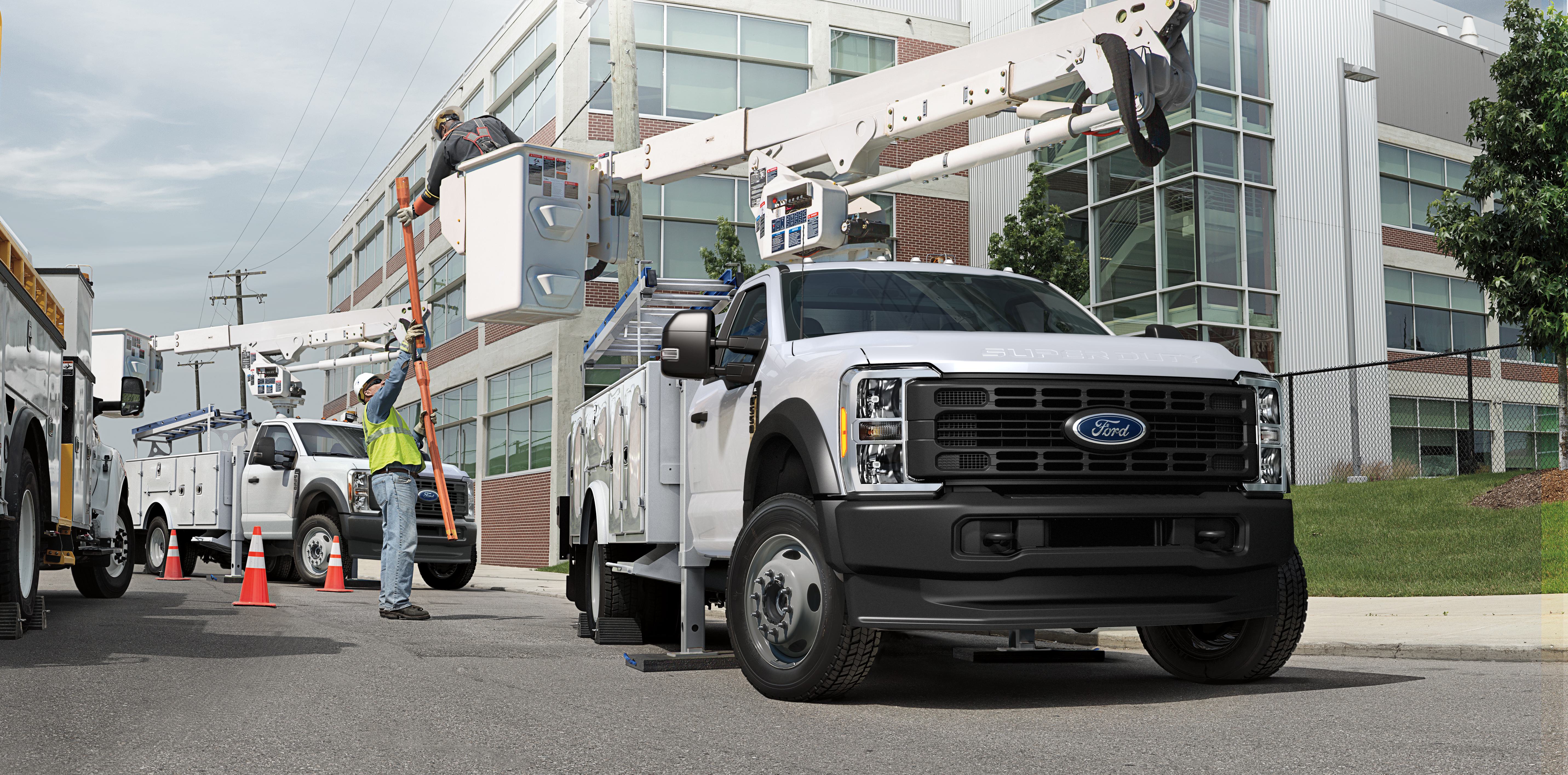 A utility crew works with two large vehicles, one equipped with a cherry picker