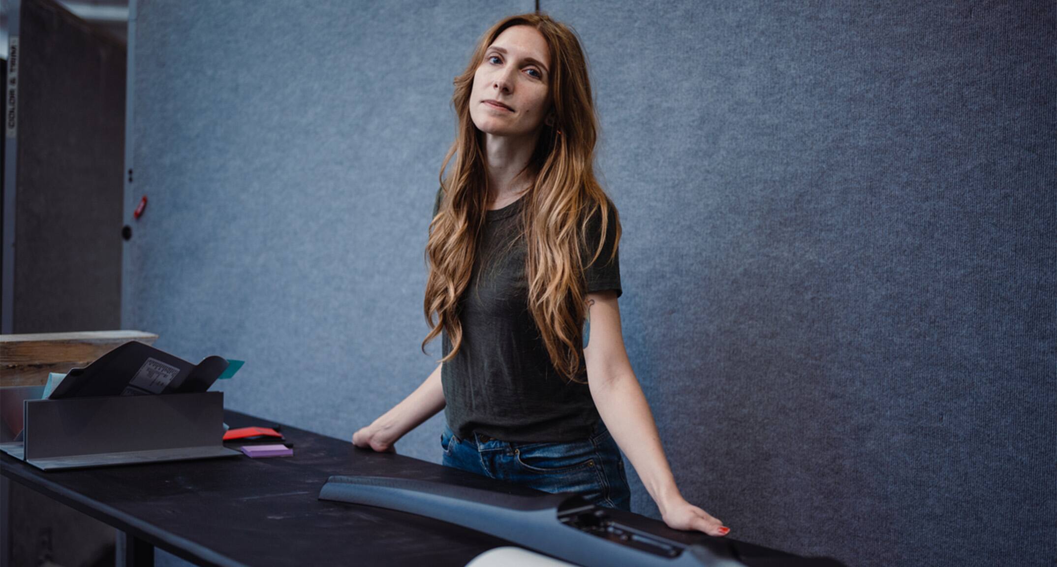 Ford Color and Materials Designer Angela Bell stands at a desk and looks at the camera.