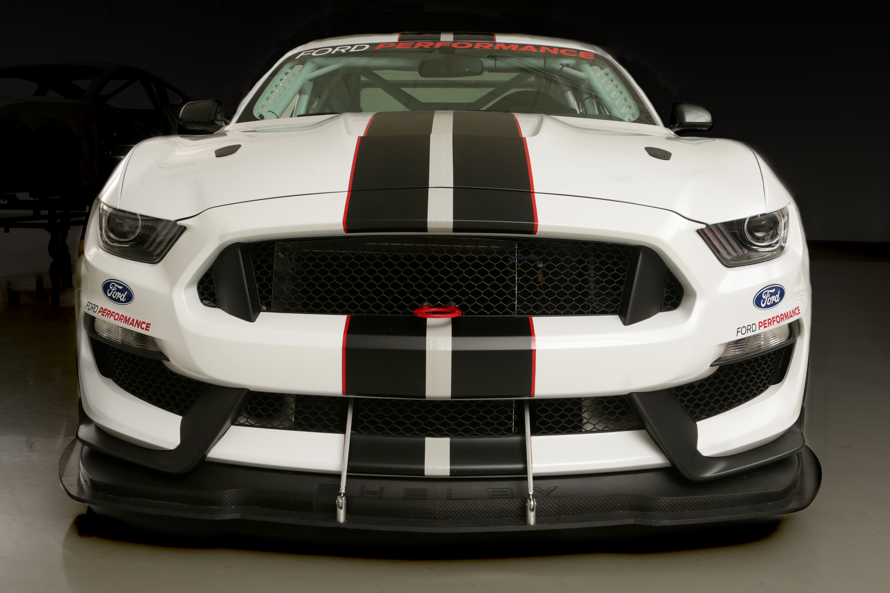 A white Mustang with two stripes down the middle viewed from the front.