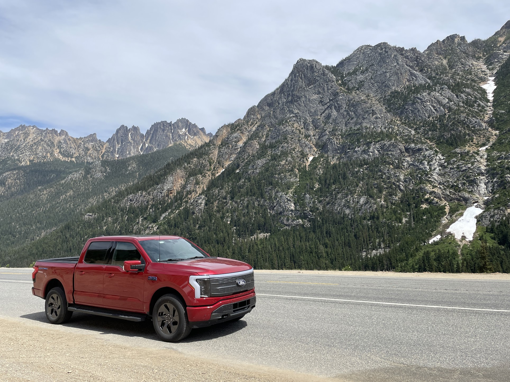 A red F-150 Lightning with a mountainous formation in the background.