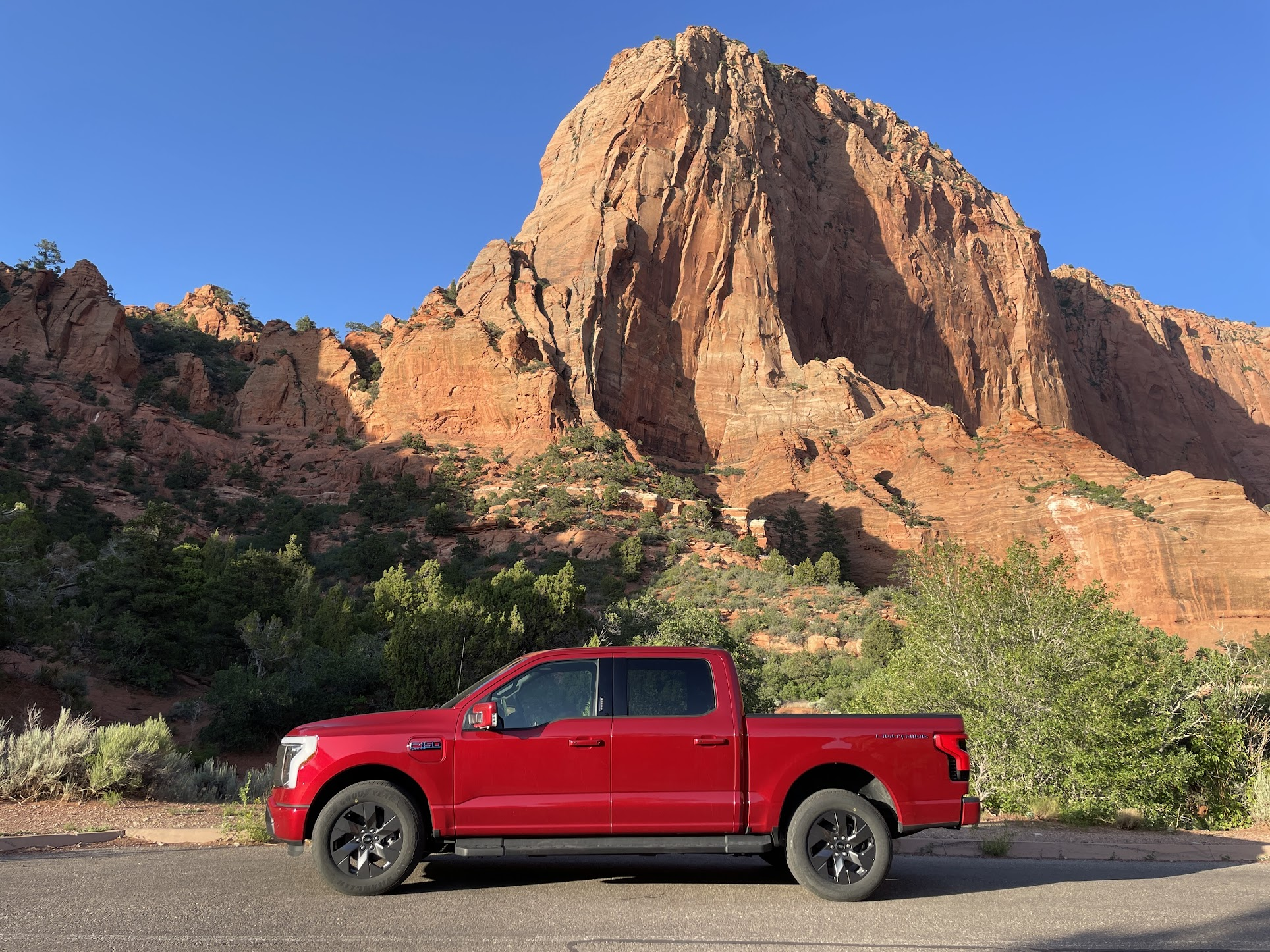 A red F-150 Lightning with a mountainous formation in the background.