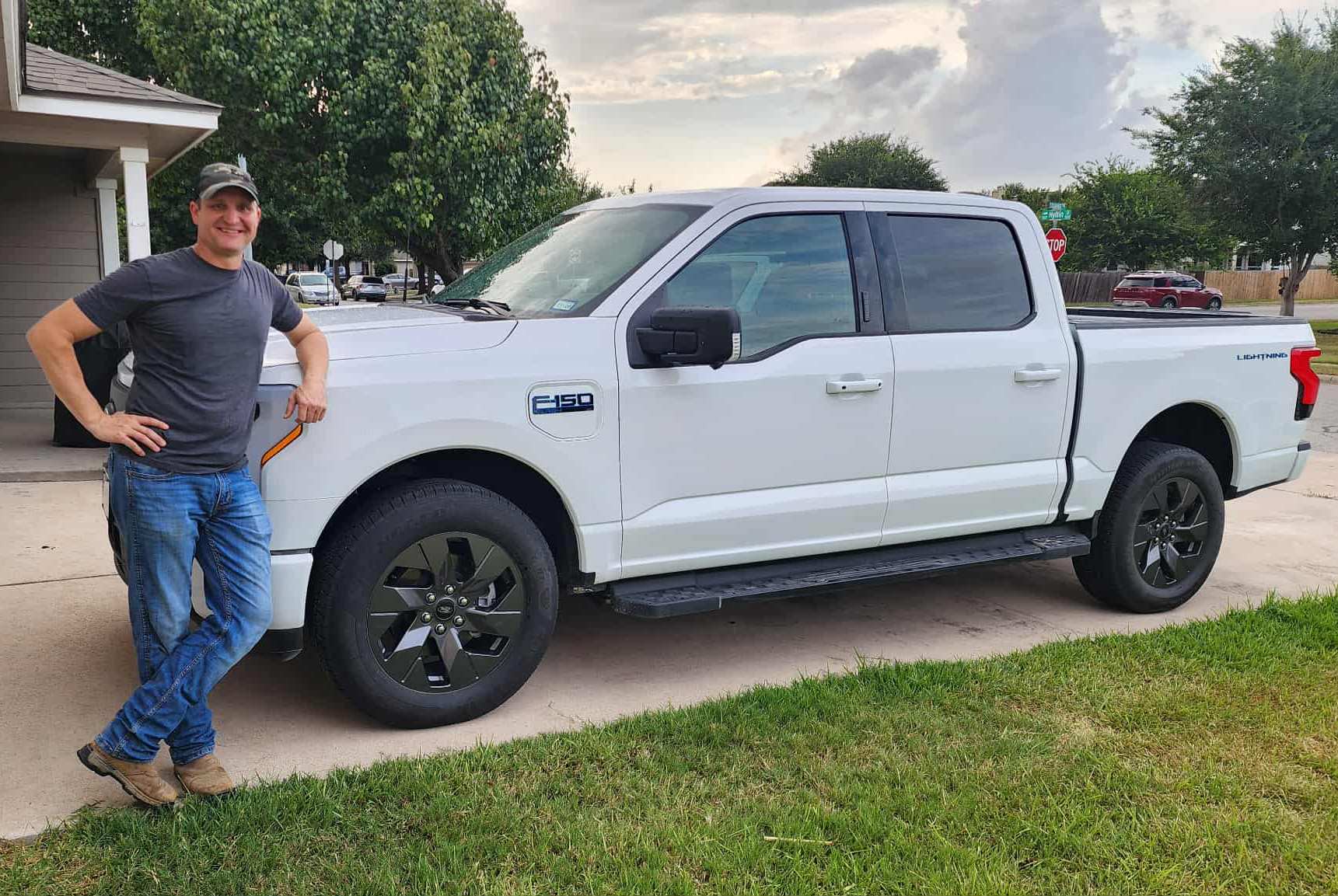 A man poses next to his white Ford F-150 Lightning truck.
