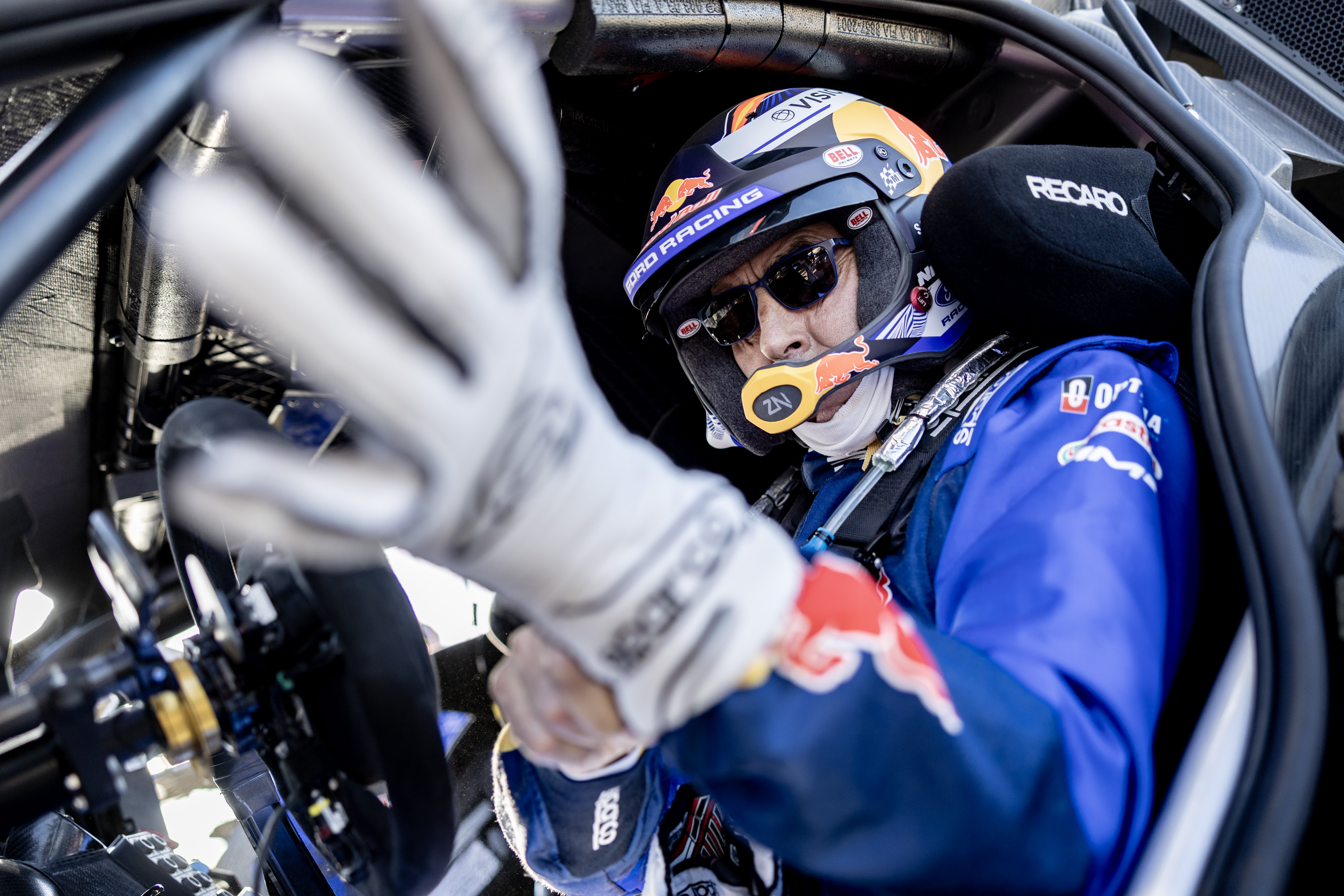 A close-up of Nani Roma as he puts on his gloves in the driver's seat at Dakar. 