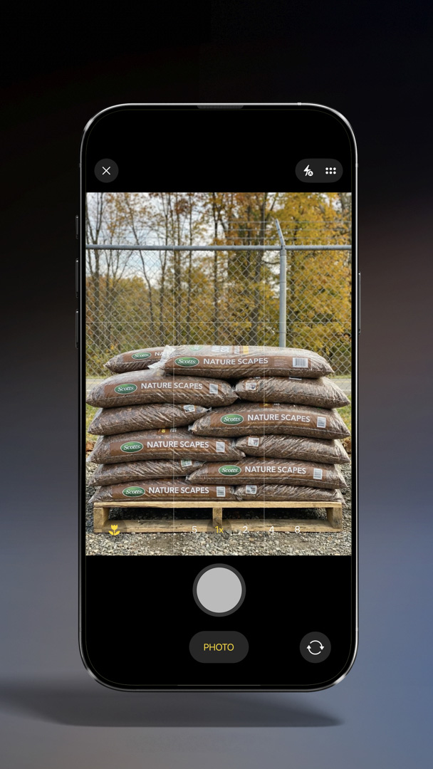 A phone screen displays a photo of a pile of mulch.